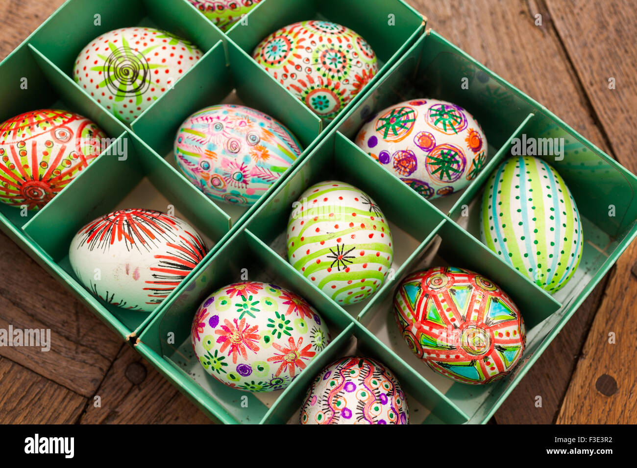 Hand painted colorful Easter eggs in green box on rustic wooden planks Stock Photo