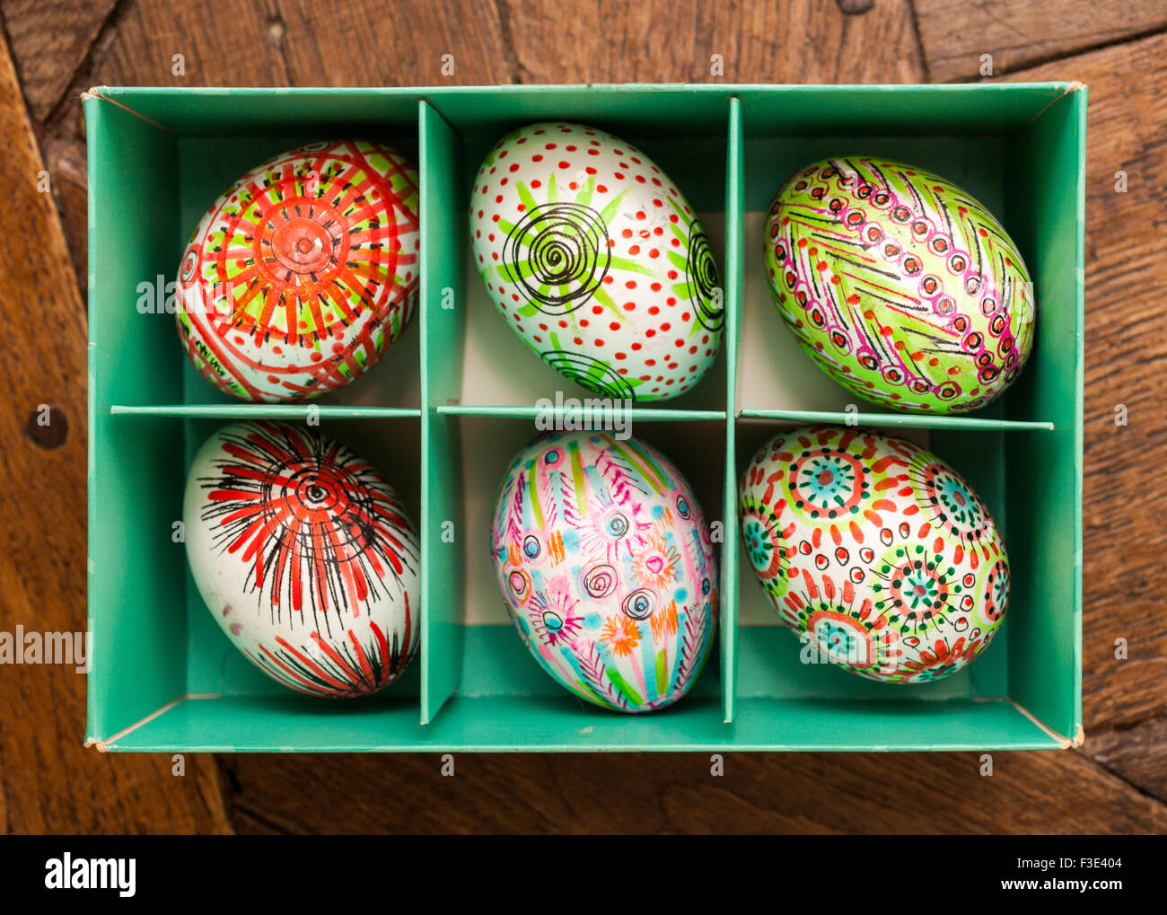 Hand painted colorful Easter eggs in green box on rustic wooden planks Stock Photo