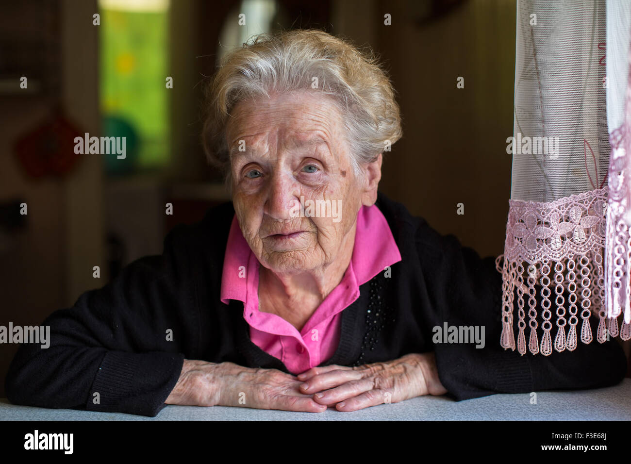 Portrait of elderly woman sitting at the table of the house Stock Photo ...