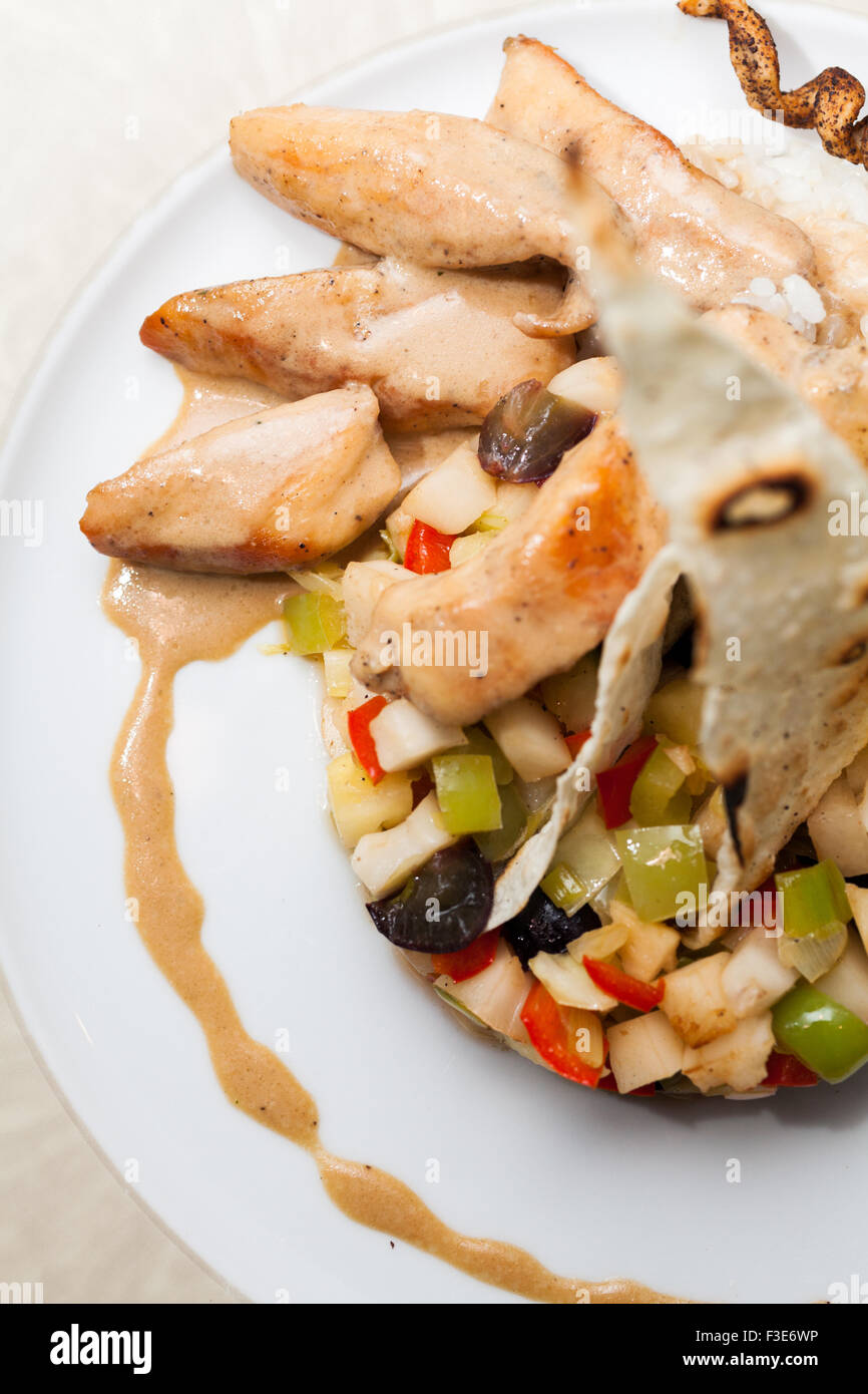 Chinese dish; chicken with sweet peppers, green peas and rise with fried pie at the top Stock Photo