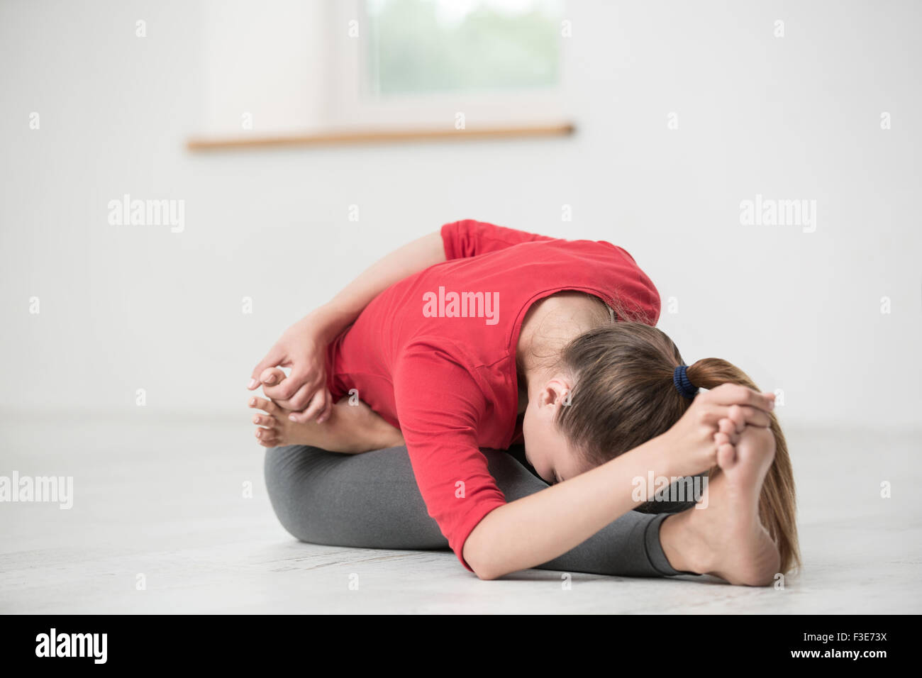 Portrait of a young woman doing stretching exercises in gym Stock Photo