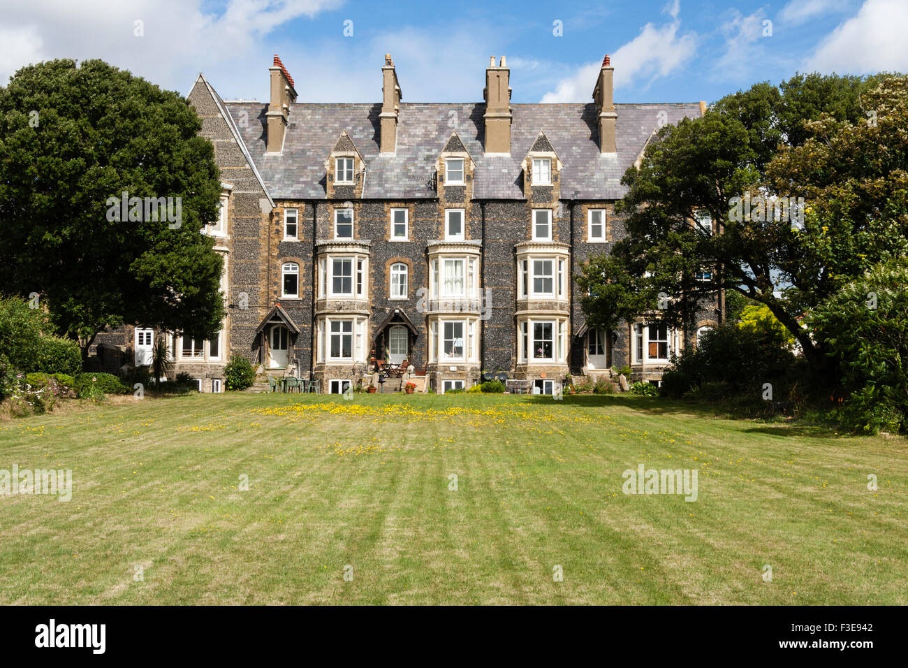 England, Ramsgate. Block of four 19th century three story flint clad terrace houses with bay windows built in Gothic architecture style, lawn in front. Stock Photo