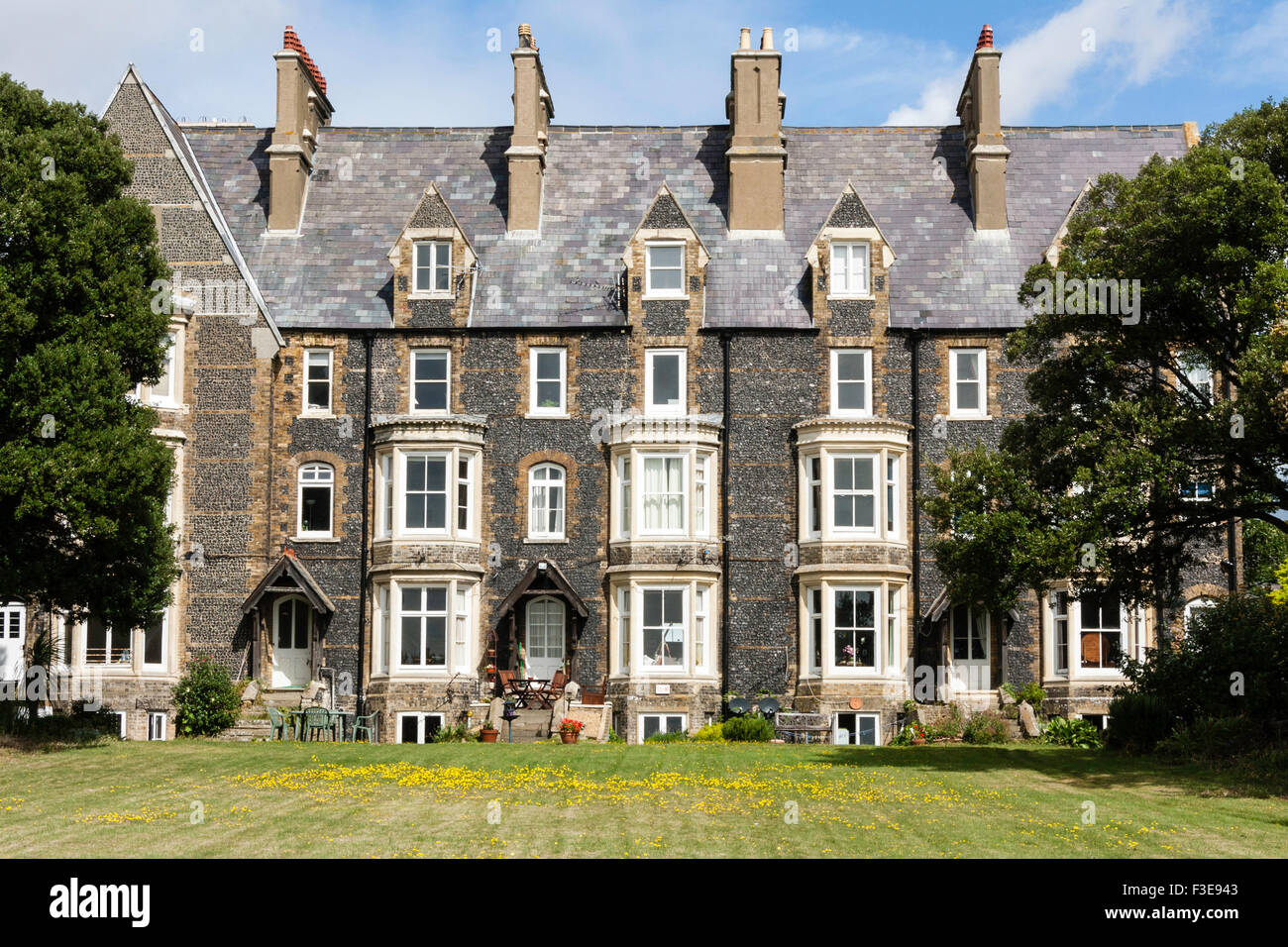 England, Ramsgate. Block of four 19th century three story flint clad terrace houses with bay windows built in Gothic architecture style, lawn in front. Stock Photo