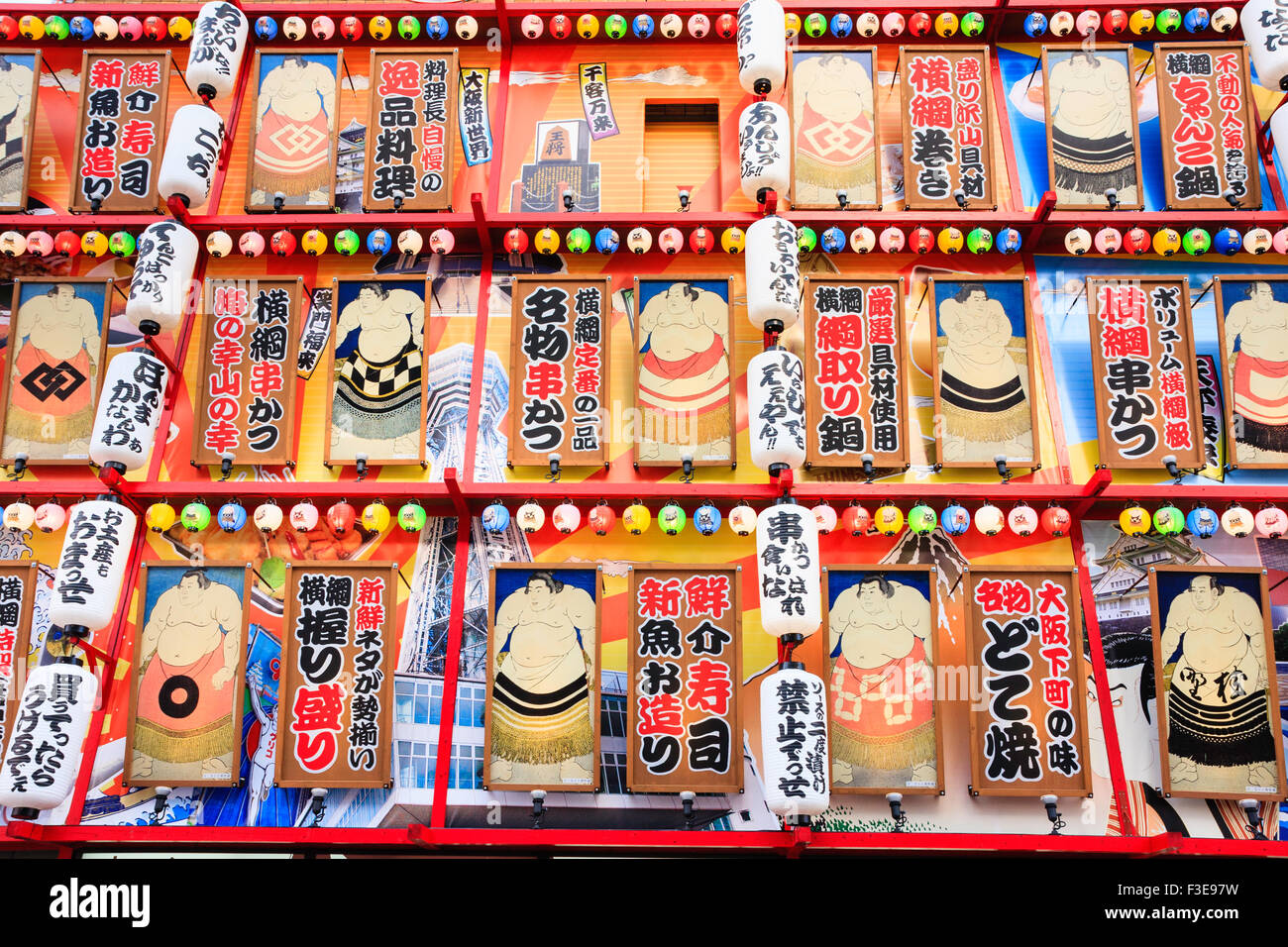 Osaka, Shinsekai. Restaurant with upper floors covered in rows of sumo westler drawings and signs with rows of coloured chochin, paper lanterns. Stock Photo