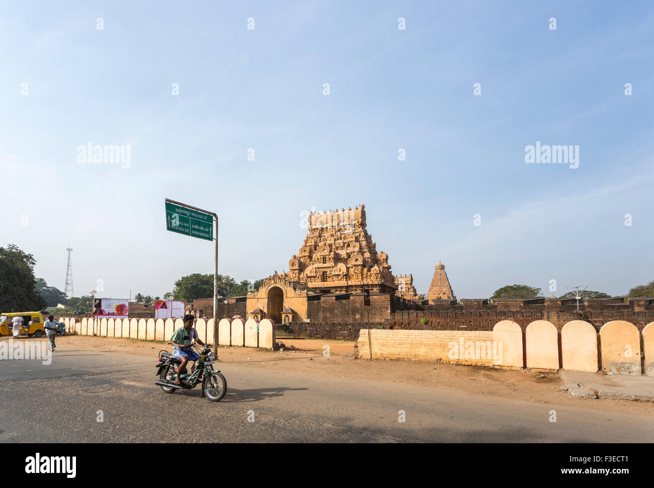 Street scene: typical Hindu temple on the roadside near Chettinad, Tamil Nadu, southern India on a sunny day with blue sky, local man riding on moped Stock Photo