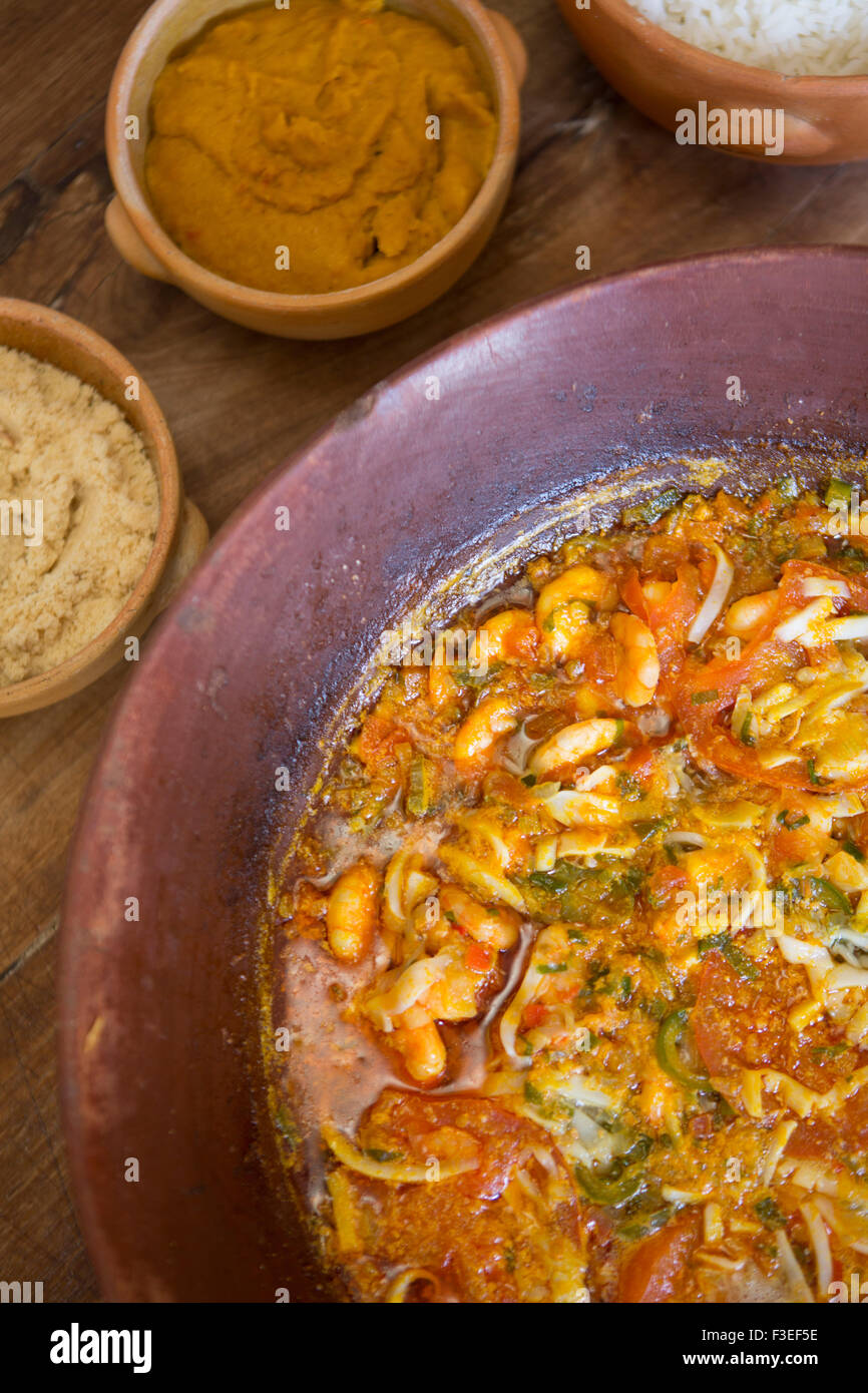 Brazil, Bahia. Moqueca - a stew of fish or shrimp, dende palm oil, coconut milk, tomato, onion  and coriander. Served with vatapa paste & condiments Stock Photo