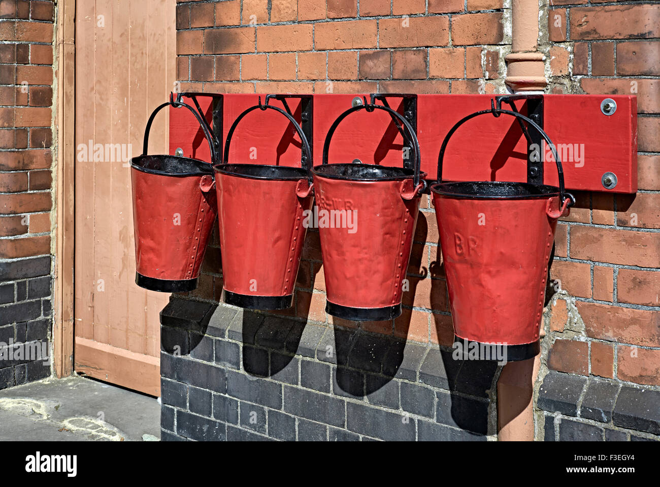 Vintage emergency sand filled red fire buckets displayed at Toddington Historic train station Nr. Broadway Cotswolds England UK Stock Photo