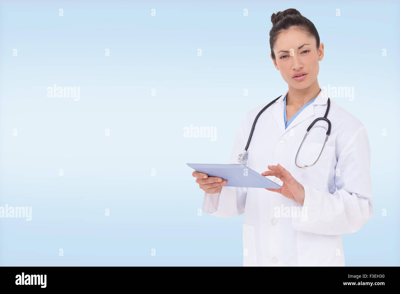 Composite image of focused doctor using her tablet pc Stock Photo