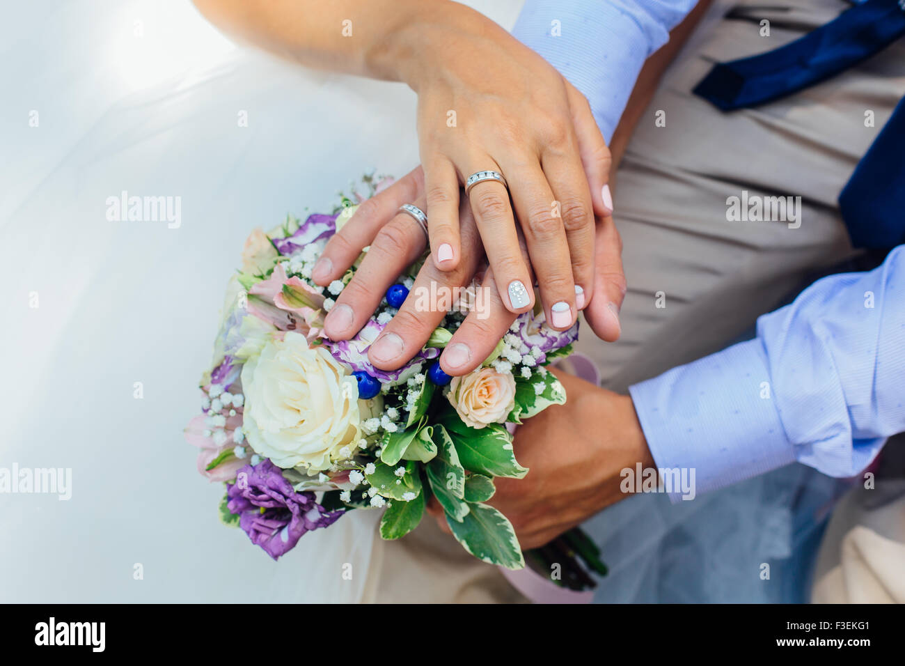 Hands of the bride and groom on the wedding bouquet Stock Photo - Alamy