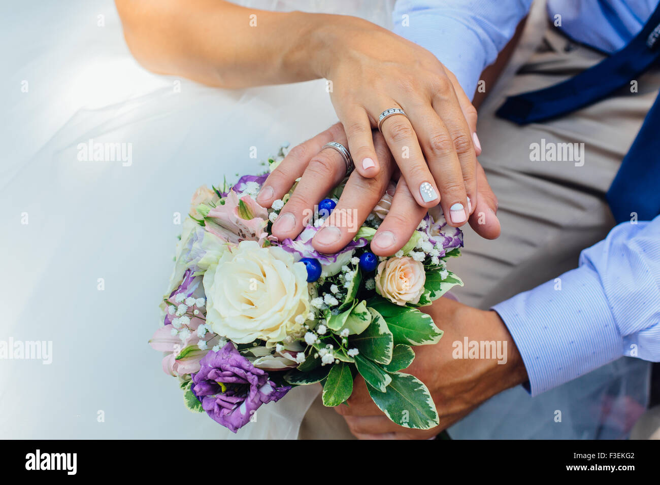 Hands of the bride and groom on the wedding bouquet Stock Photo - Alamy