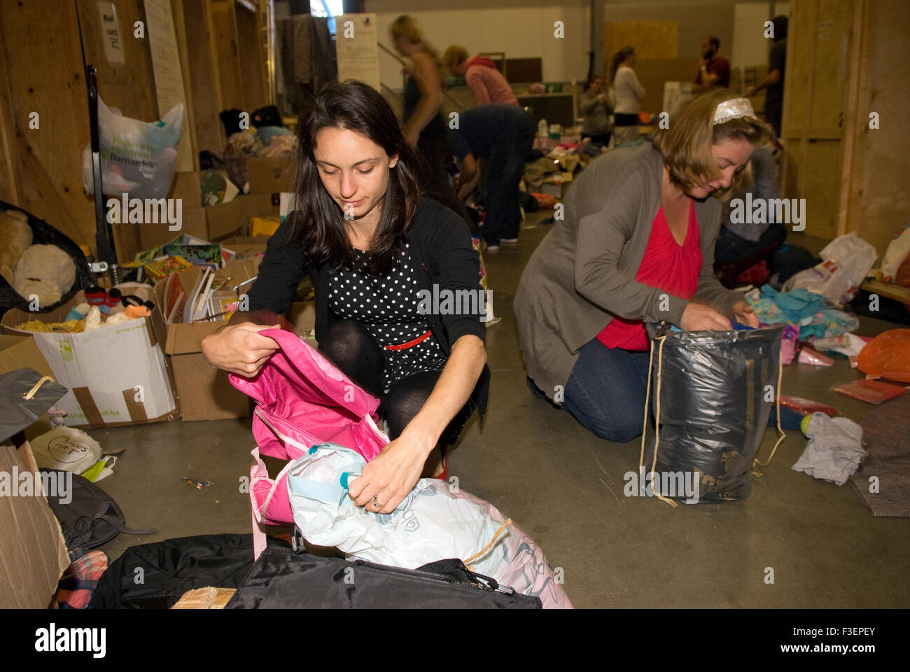 Volunteers in a shipping company's warehouse packing up donated items of clothing and other non-perishable items for shipping... Stock Photo