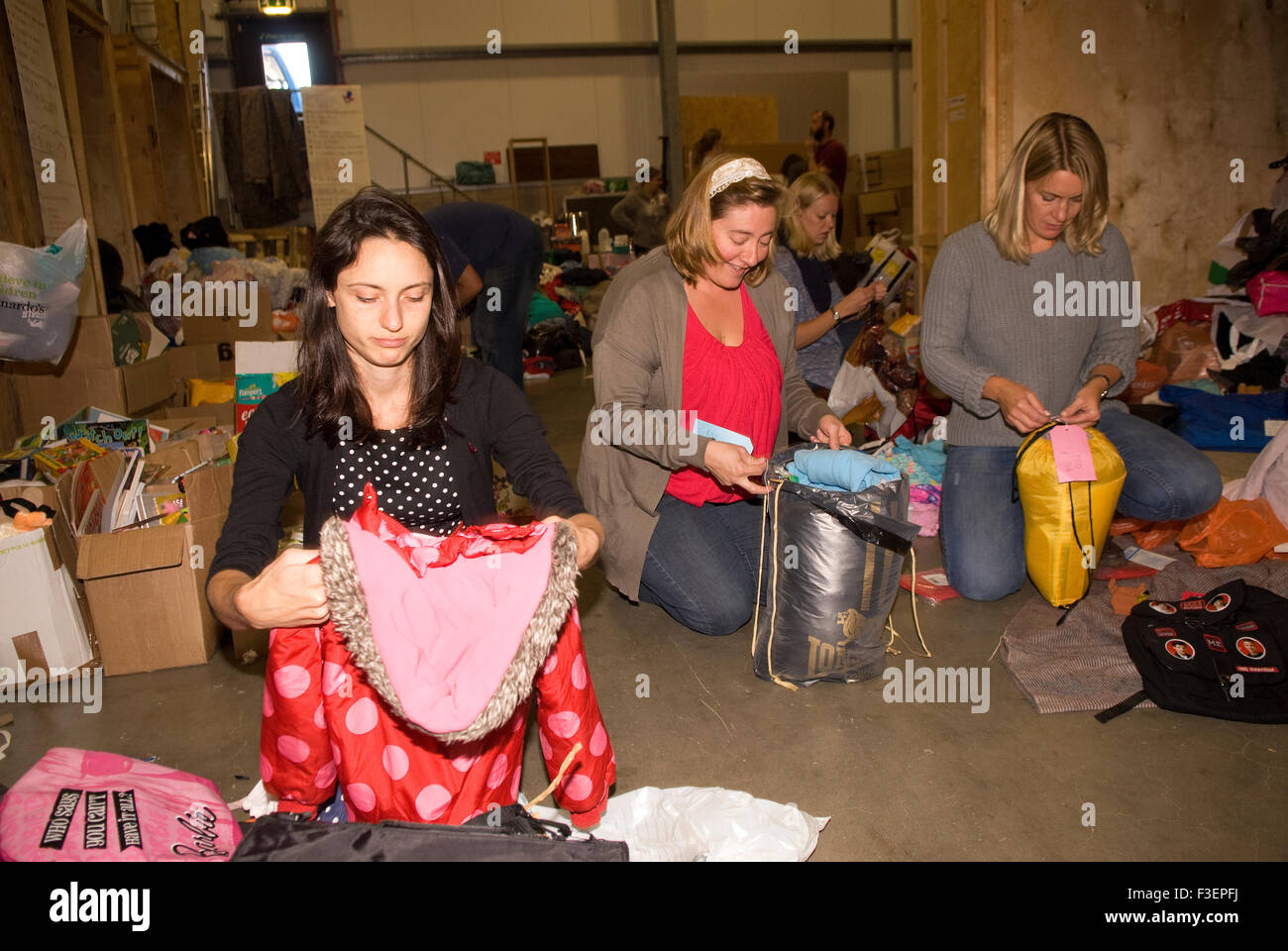 Volunteers in a shipping company's warehouse packing up donated items of clothing and other non-perishable items for shipping... Stock Photo