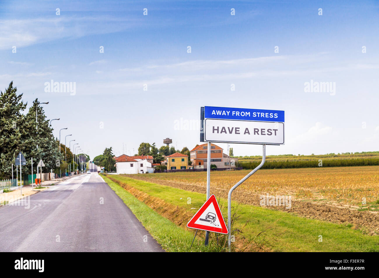 fake road sign of a quiet countryside village inviting to have a rest away from stress Stock Photo
