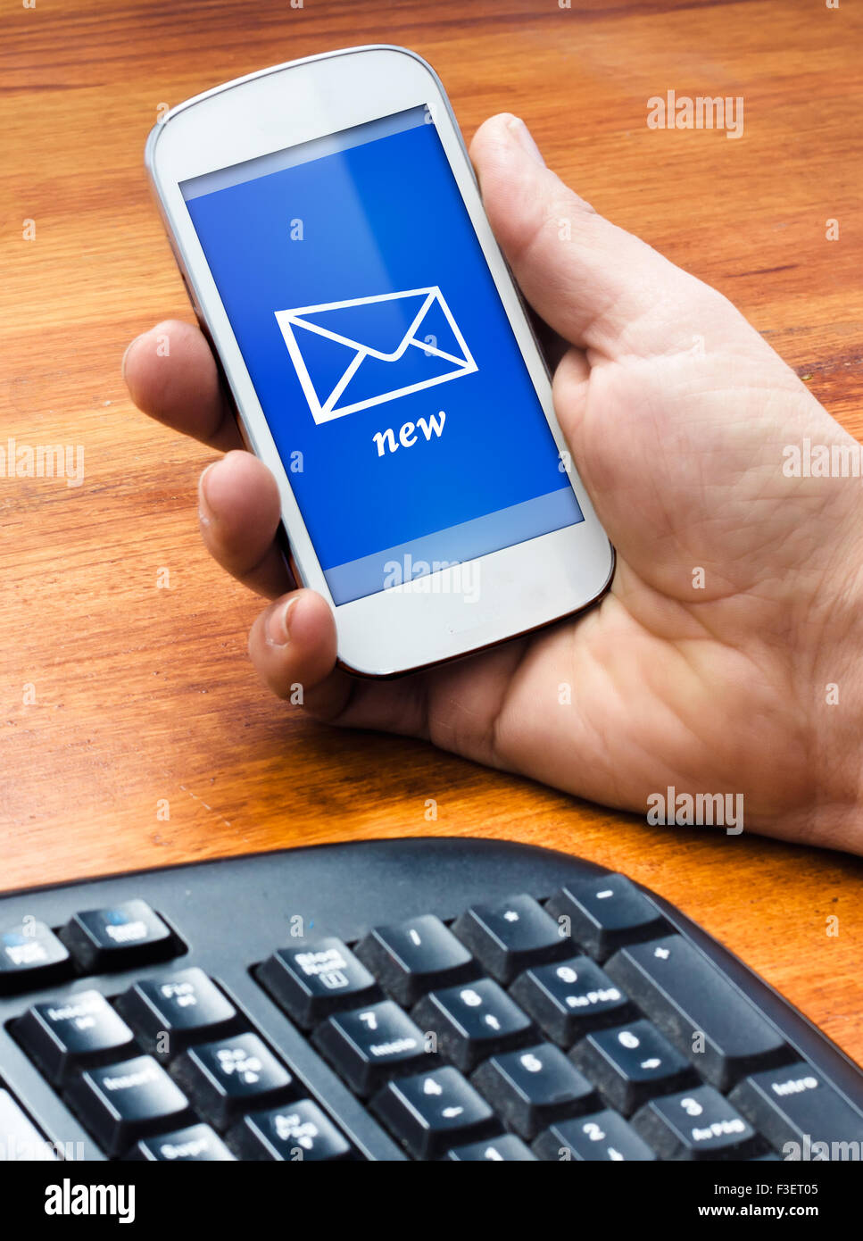 A man holding phone on the table with a new message at screen