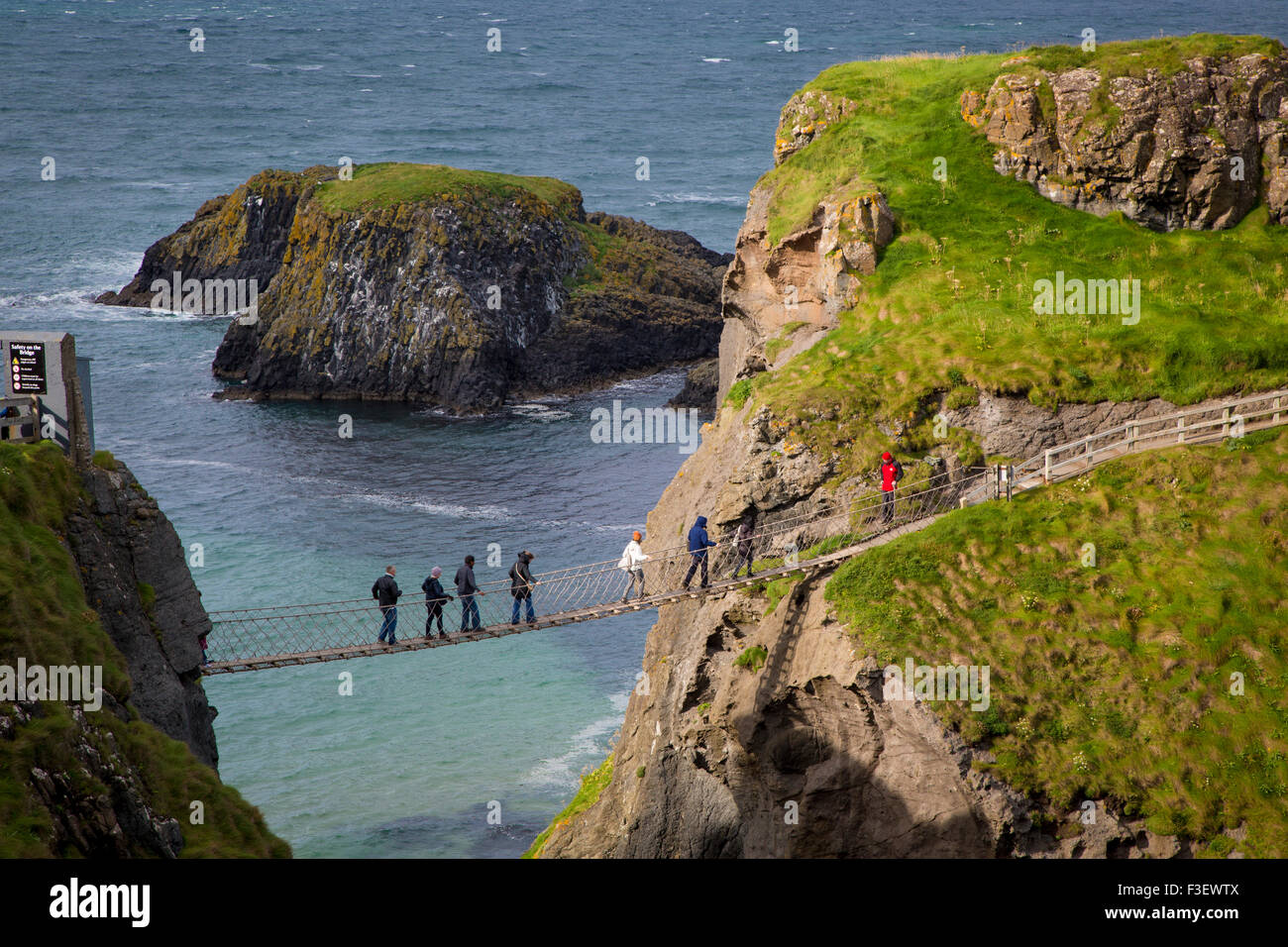 Tourists walk across the Carrick-a-Rede Rope Bridge along the north coast, County Antrim, Northern Ireland, UK Stock Photo