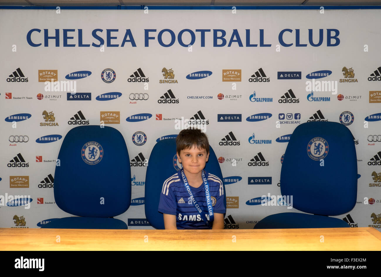 8 year old boy on organised tour of Chelsea Football club,sitting in room for [ress conferences, London, UK Stock Photo
