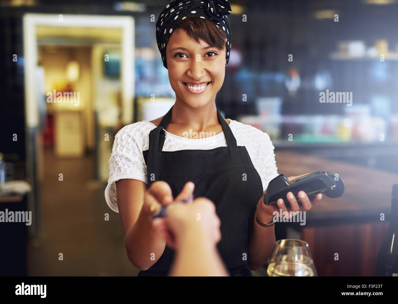 Smiling waitress or small business owner taking a credit card from a customer to process through the banking machine in payment Stock Photo