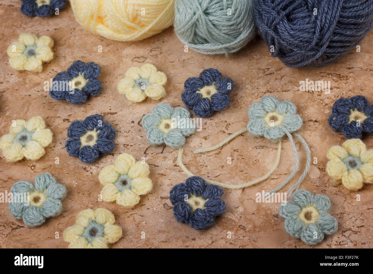 Handmade colorful crochet flower with skein on marble table. Selective focus Stock Photo