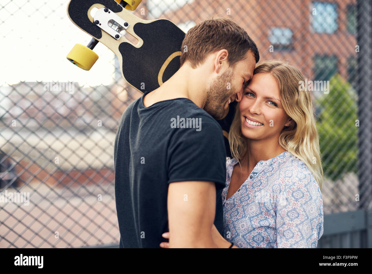 Couple loving each other, big city couple, man holding skateboard Stock Photo