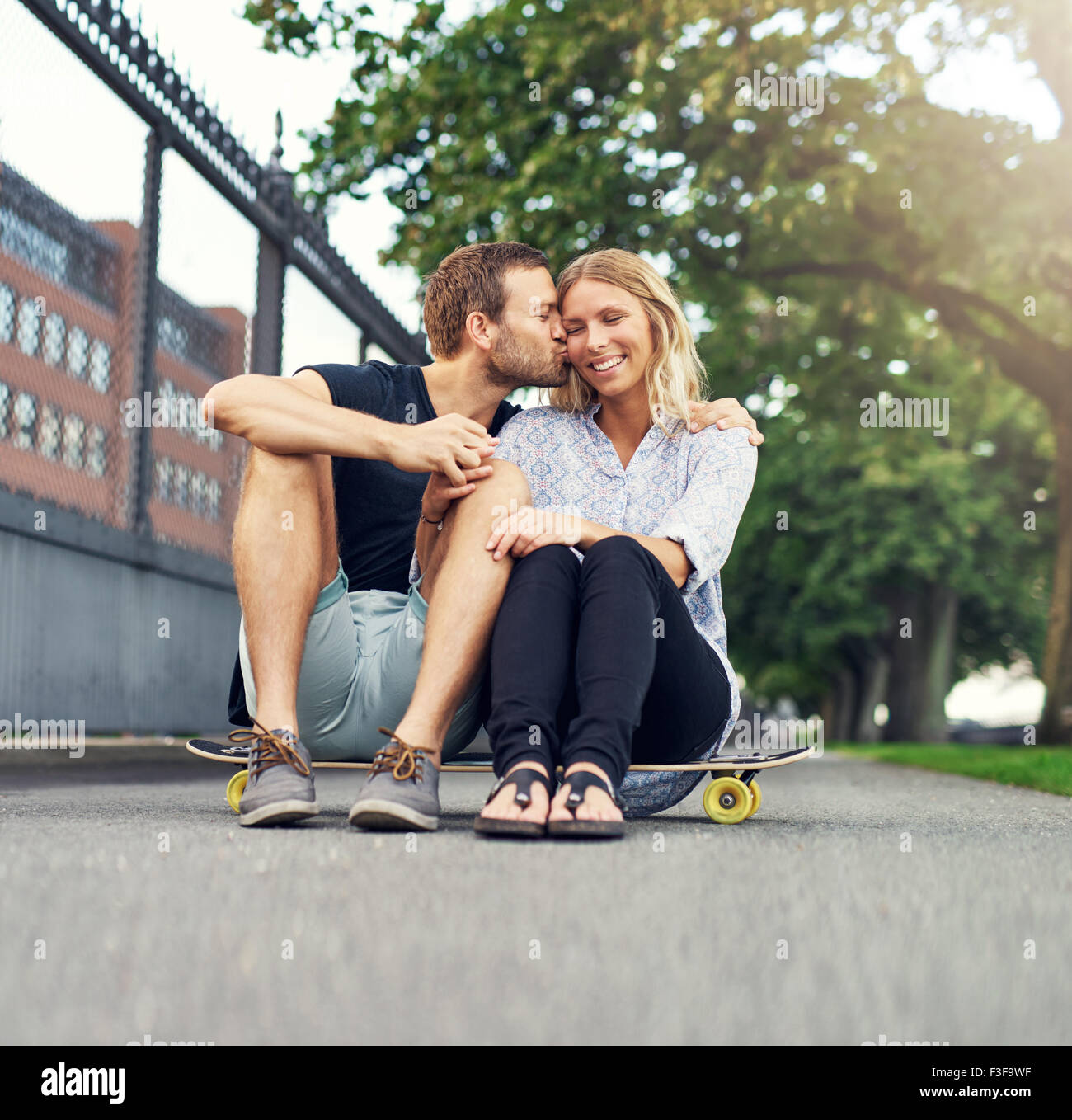 Man kissing woman on her cheek while sitting in a park Stock Photo