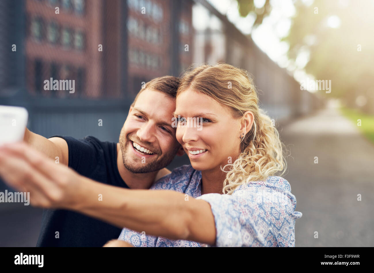 Beautiful Couple Taking a Selfie While Sitting in a Park Stock Photo
