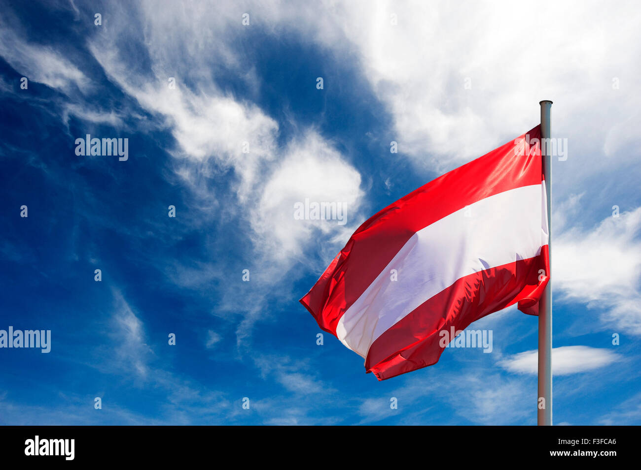 Flag of Austria against blue sky with white clouds Stock Photo