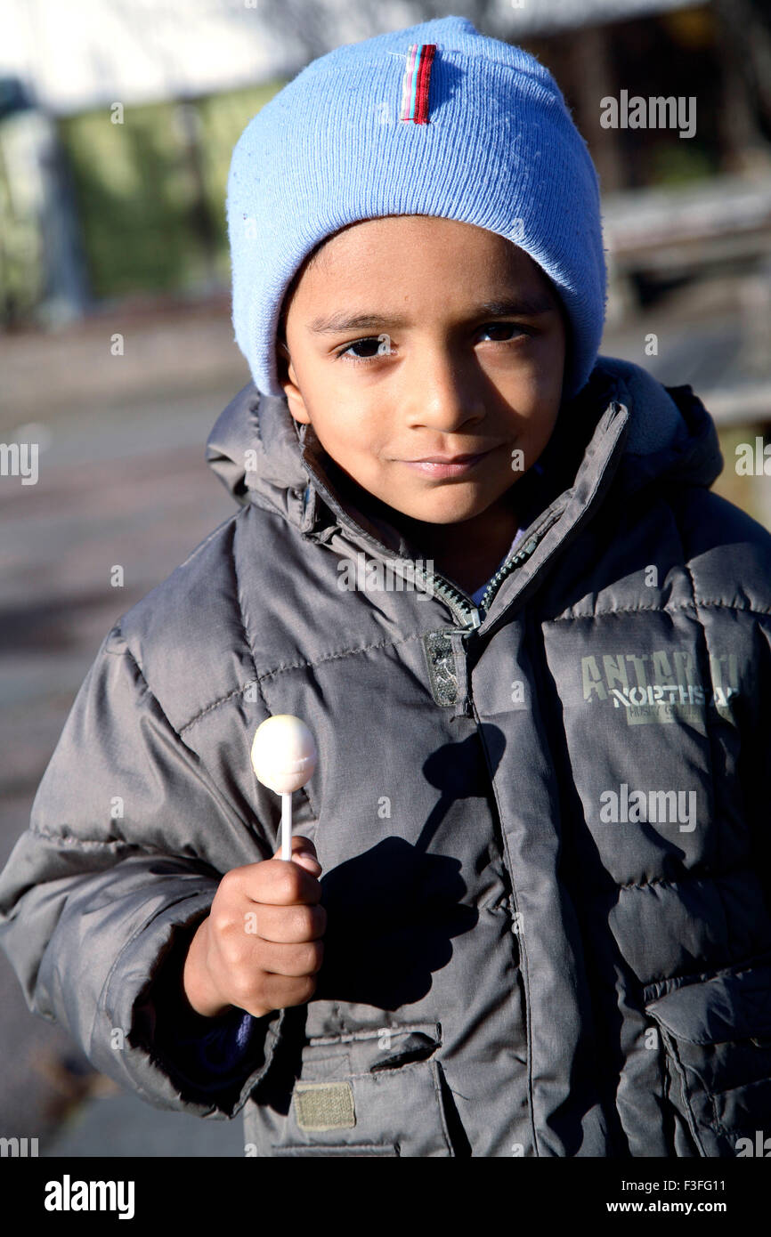 Four years old boy holding lollipop in hand wearing winter clothing ; Sweden MR#468 Stock Photo
