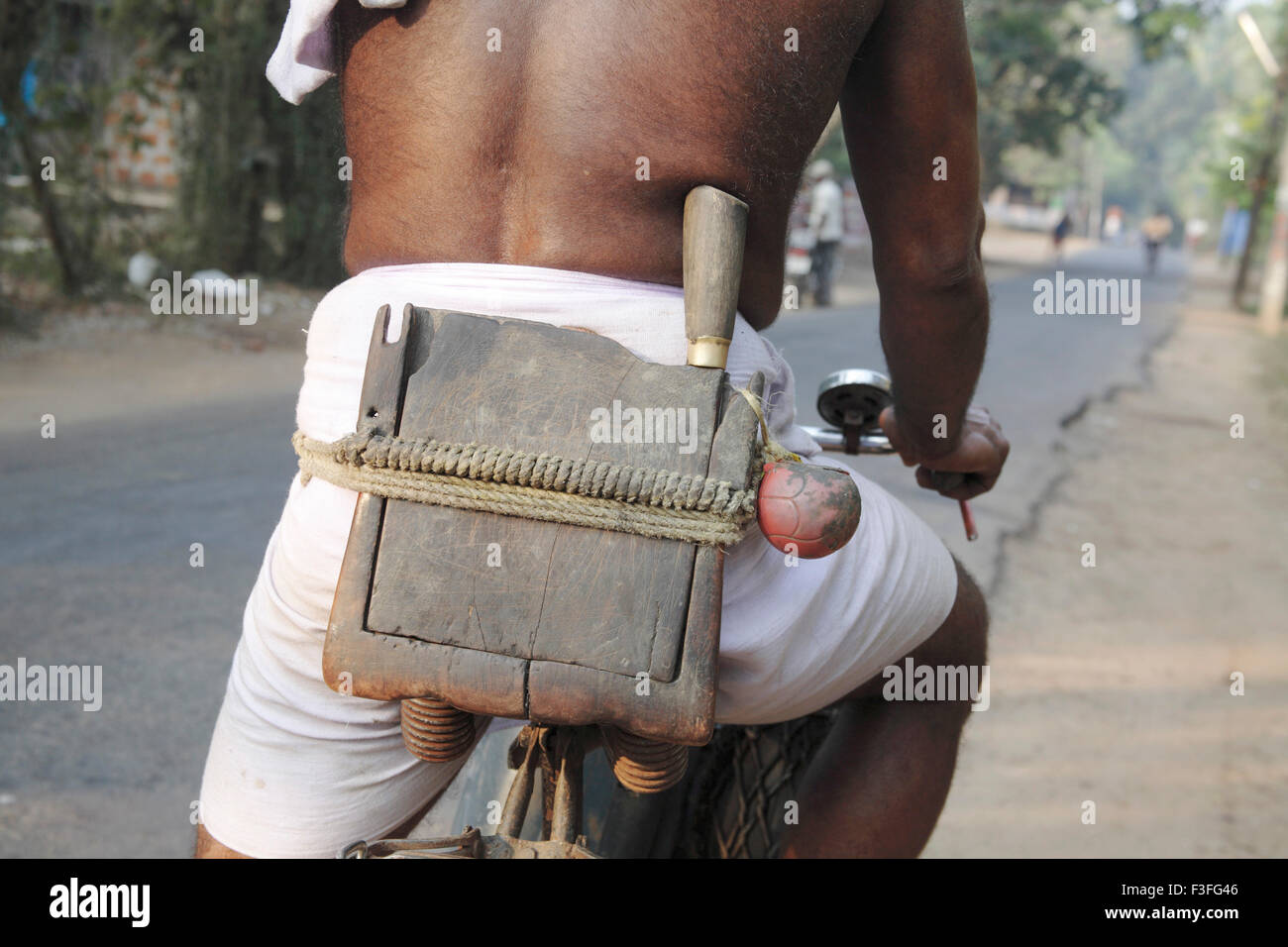 Coconut tree climber toddy collector toddy taper tools tied to waist wearing lungi waist cloth ; Kerala ; India Stock Photo