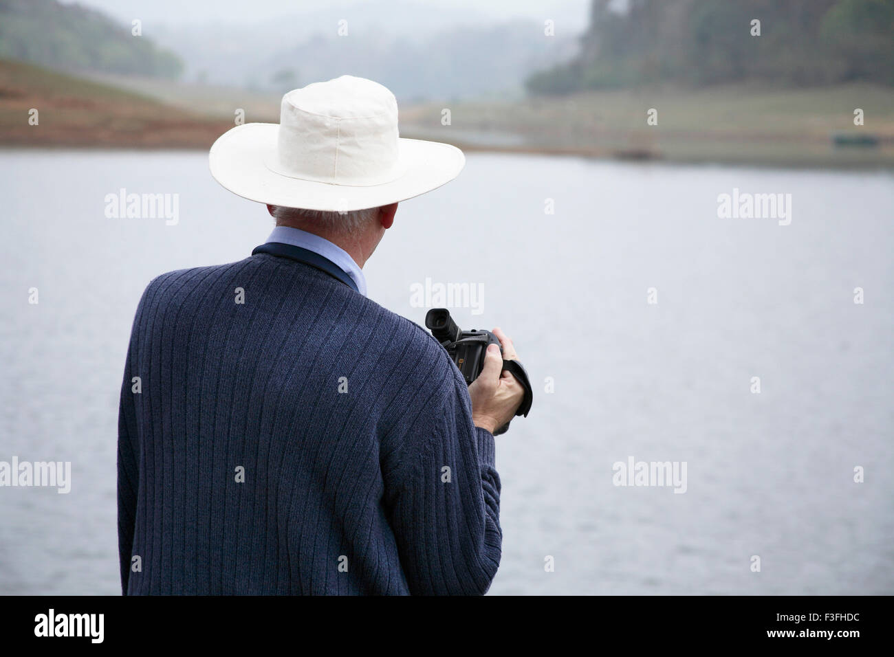 Foreigner holding video camera and observing at Periyar Wildlife Sanctuary from boat ; Thekkady ; Kerala ; India Stock Photo