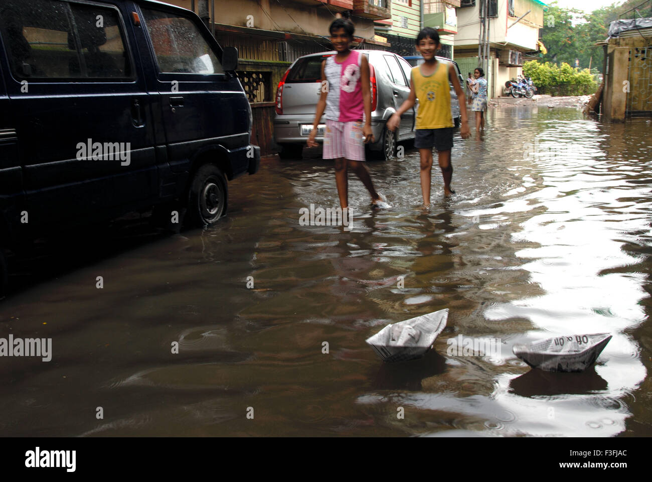 Children sailing paper boats on flooded street Stock Photo