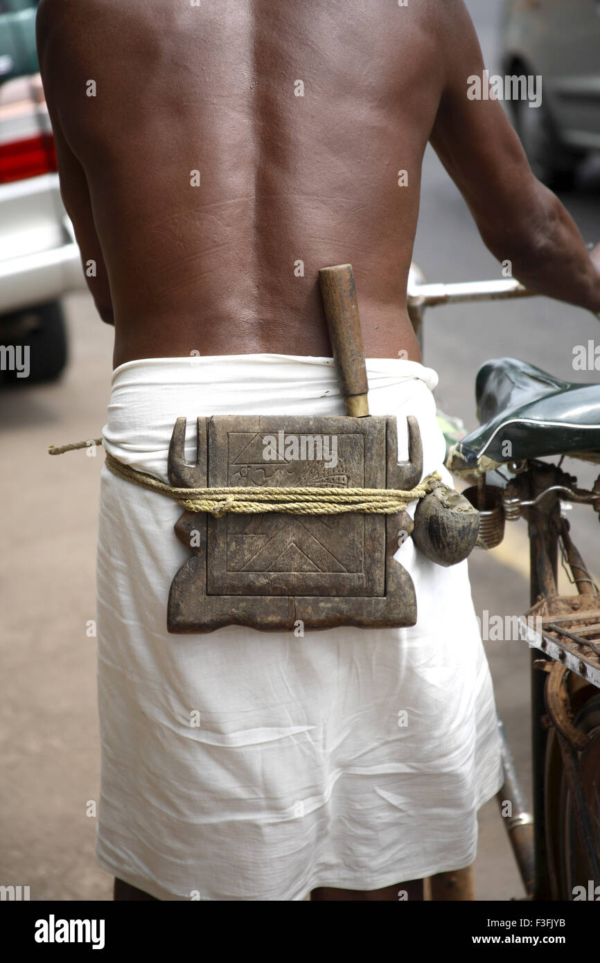 Coconut tree Climber ; toddy collector ; Toddy taper tools tied to waist wearing Lungi waist cloth ; Kerala ; India Stock Photo