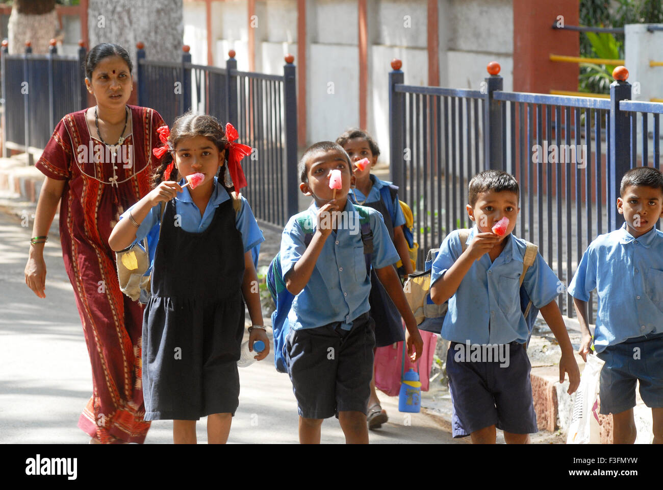 School children eating flavoured ice candy ; Bombay now Mumbai ; Maharashtra ; India Stock Photo
