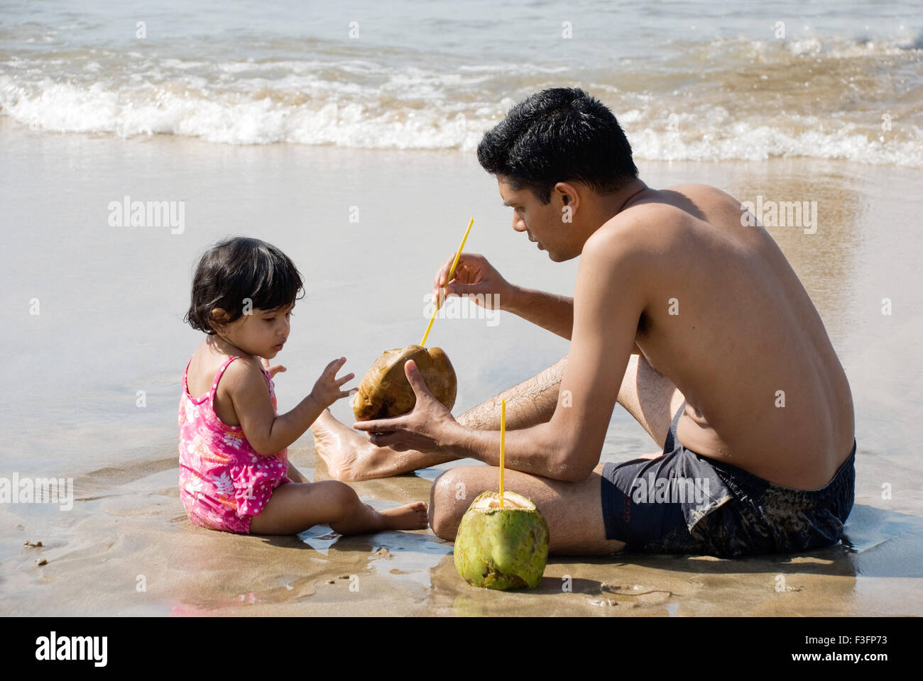 Father and daughter cooling off on the beach ; Mandre beach ; Goa ; India MR Stock Photo