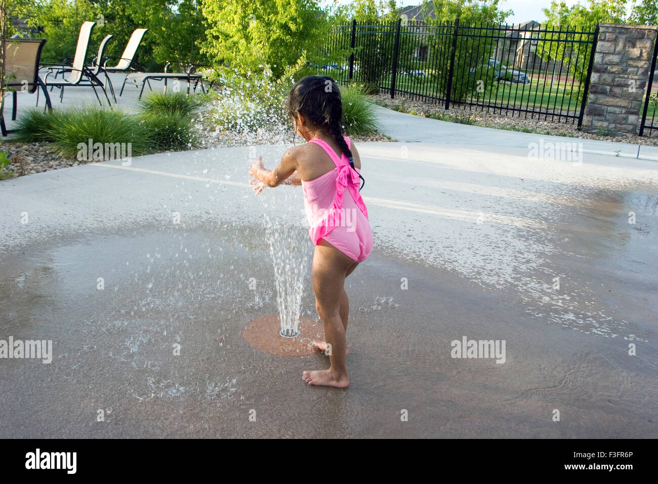 Four years old girl playing with water fountain Stock Photo