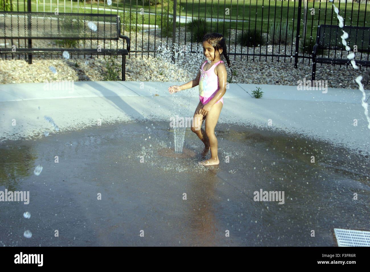 Four years old girl playing and enjoying with water fountain Stock Photo