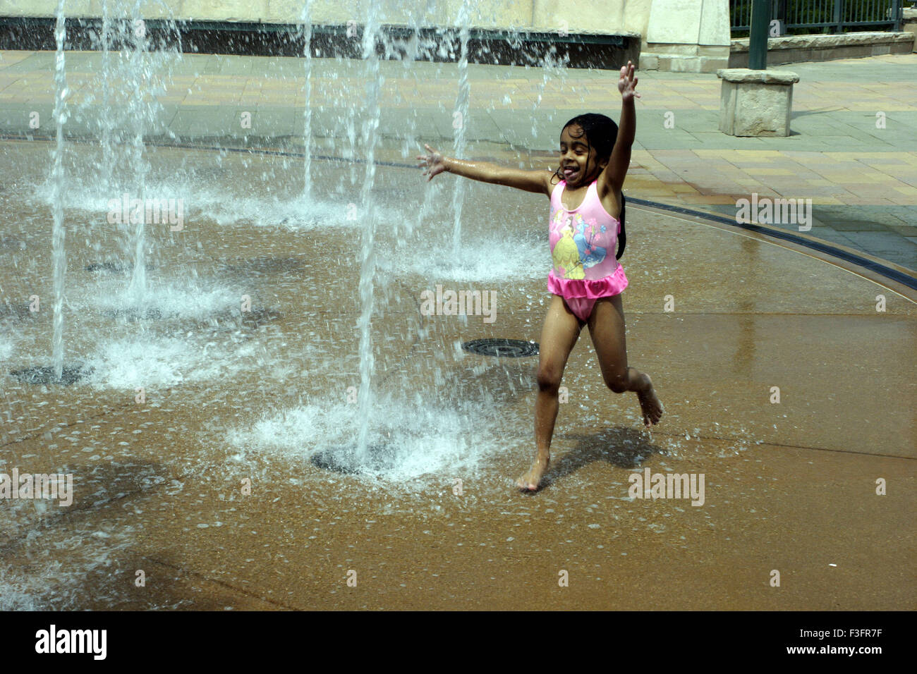 Four year old girl enjoying in fountain in summer day ; U.S.A. United States of America Stock Photo