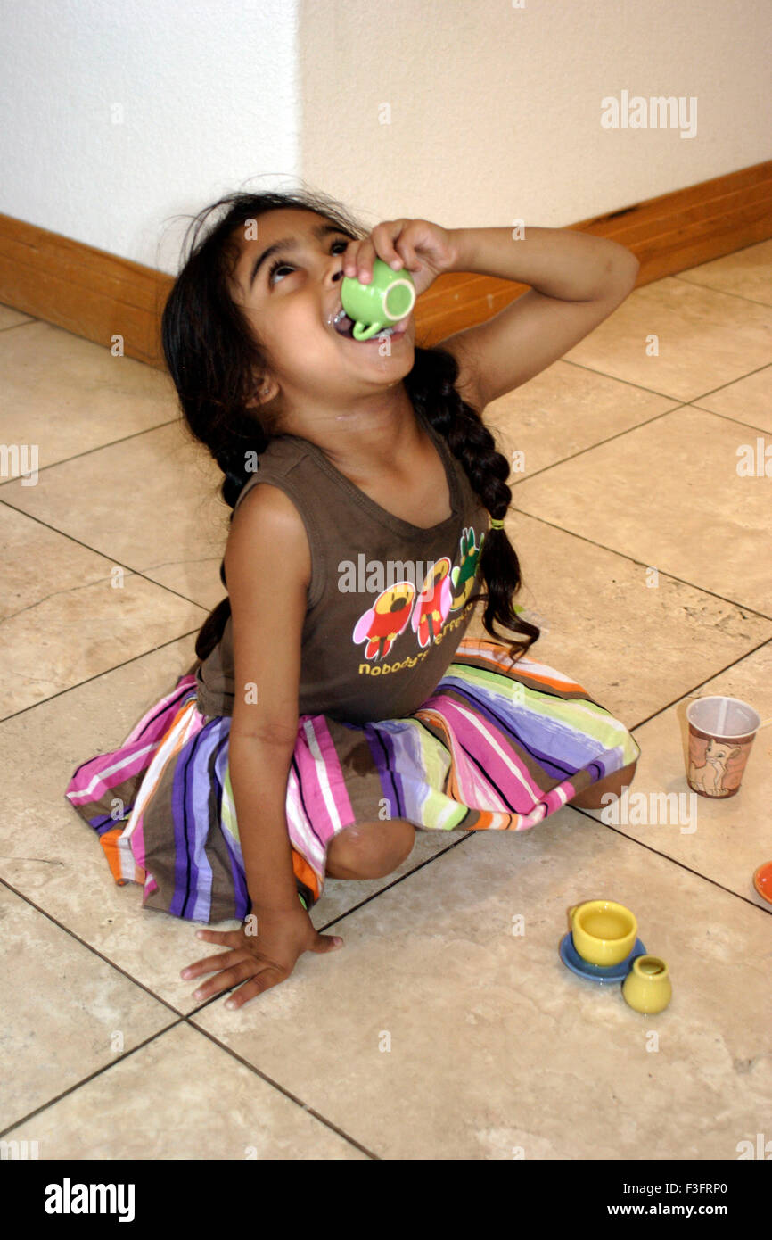 Four years old girl drinking tea from her mini toy cup MR Stock Photo