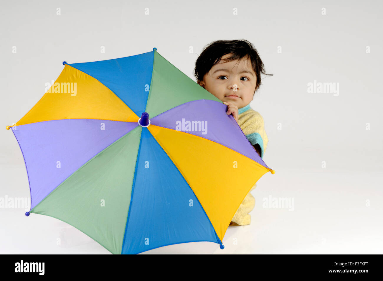 Indian Child playing Hide & Seek with Umbrella ; MR Stock Photo