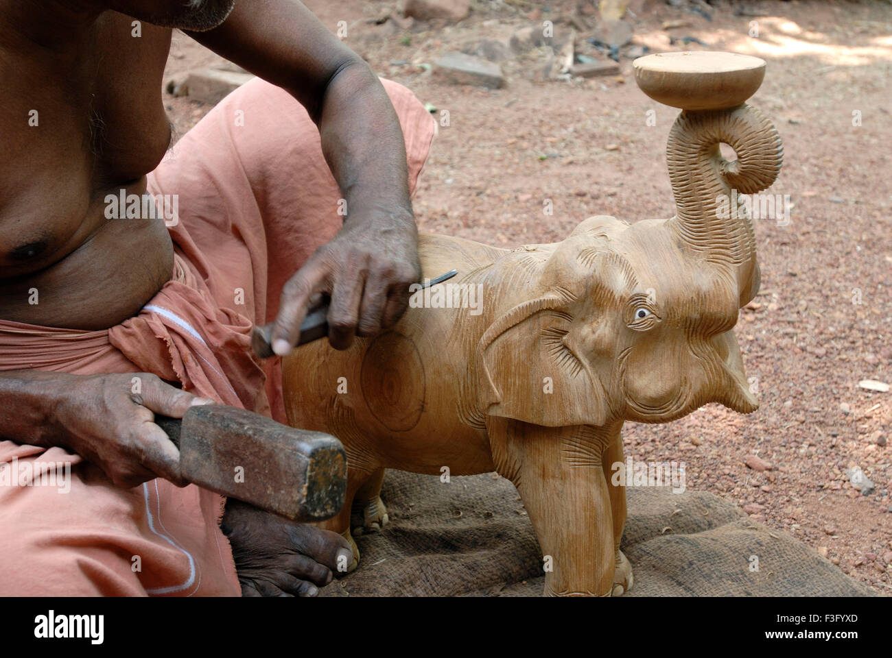 man carving teak wood elephant near Thrissur ; Kerala ; India Stock Photo