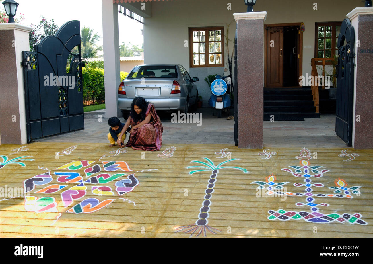 Woman making kolam or rangoli in front of house ; Pongal festival