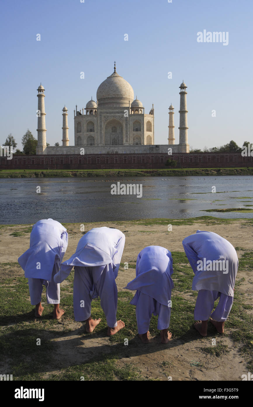 Young muslim boys performing religious prayer Namaz in front of Taj Mahal Seventh Wonders Yamuna river Agra Uttar Pradesh Stock Photo