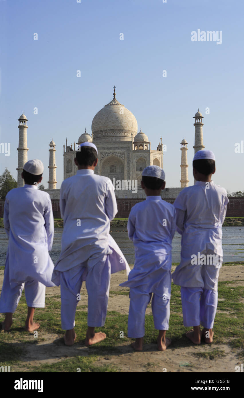 Young muslim boys performing religious prayer Namaz in front of Taj