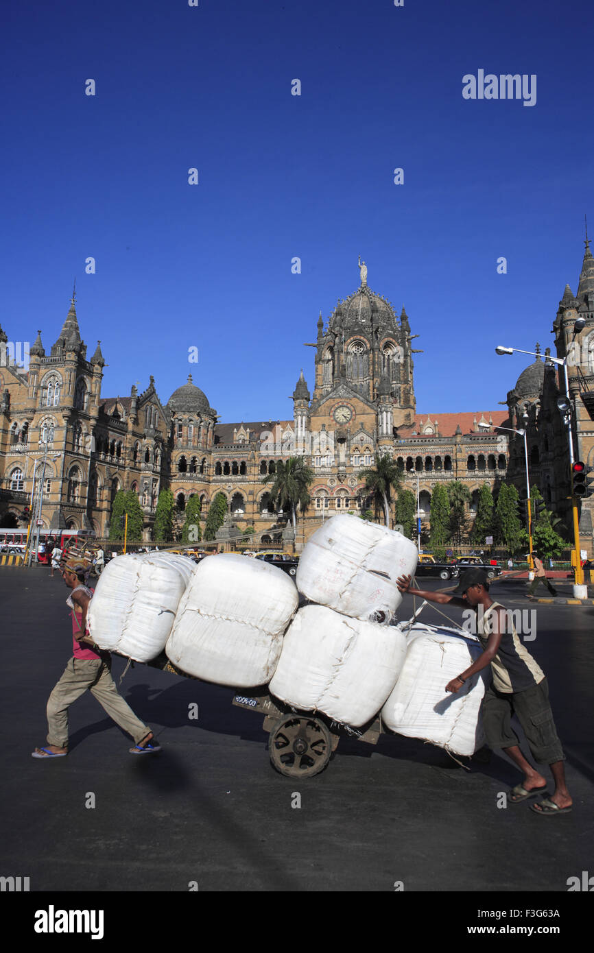 Labors pulling handcart luggage Chhatrapati Shivaji Terminus Victorian gothic revival Railway Station Bombay Mumbai Maharashtra Stock Photo