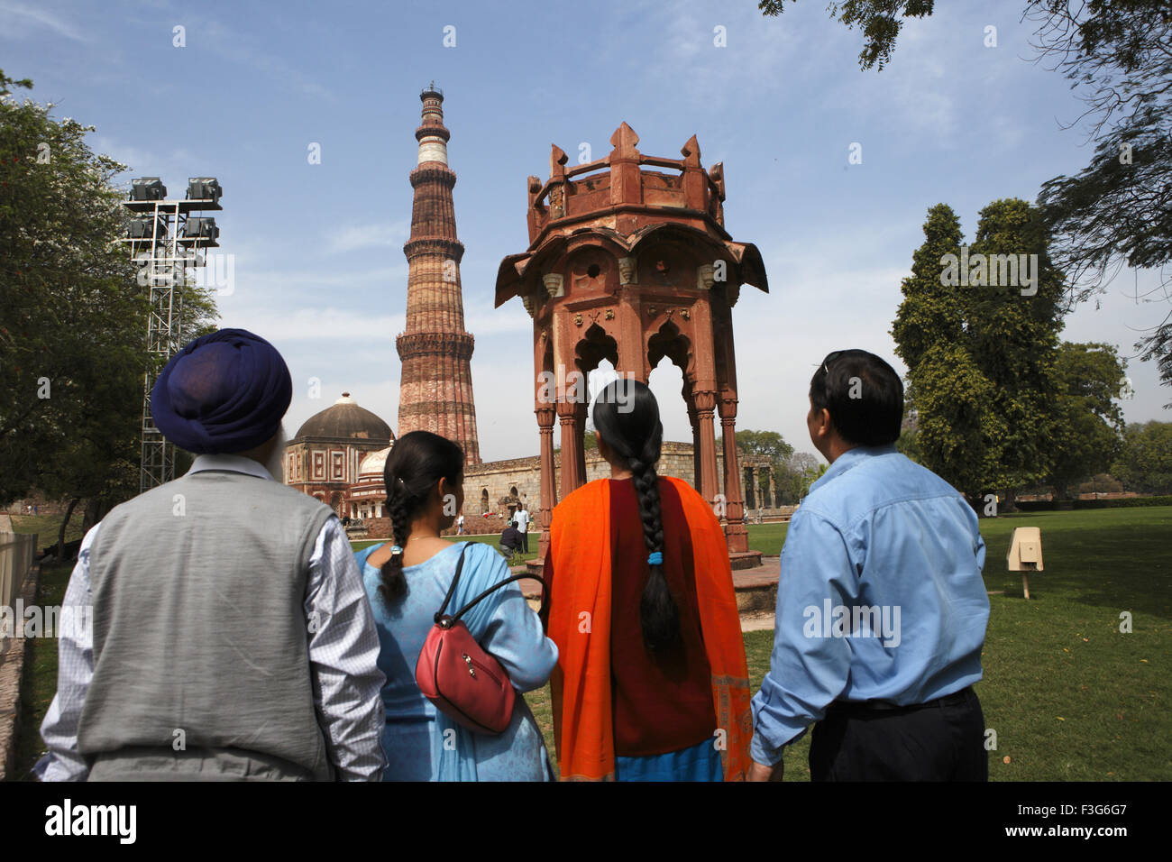 Punjabi Sikh family watching Smith's Folly and Qutb Minar built in 1311 red sandstone tower ; Indo Muslim art ; Delhi Stock Photo