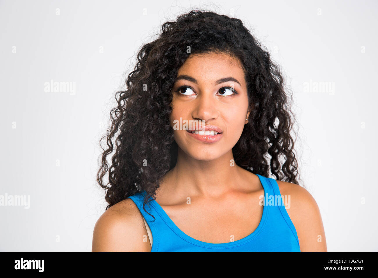 Portrait of a thoughtful afro american woman biting her lips and looking up at copyspace isolated on a white background Stock Photo