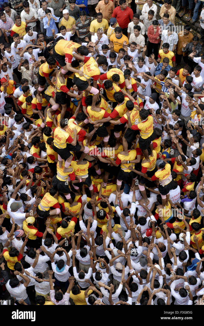 Govinda in yellow white uniform forming human pyramid ; Dahikala festival ; Dadar ; Mumbai Bombay ; Maharashtra ; India Stock Photo