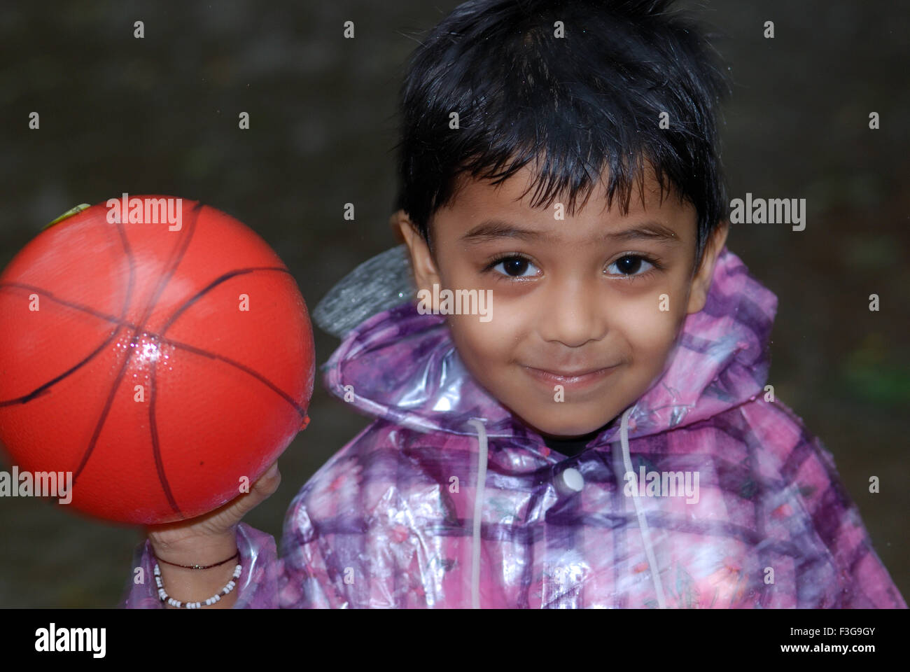 Child playing with ball in rain, India, Asia Stock Photo