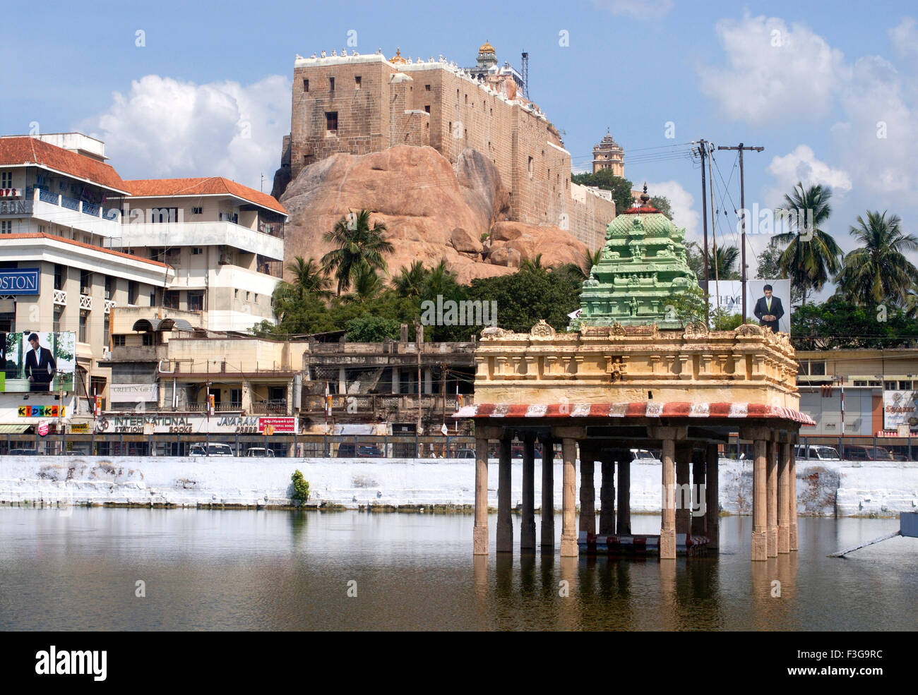 Rock fort with holy tank and pavilion surrounded by buildings and shops ...