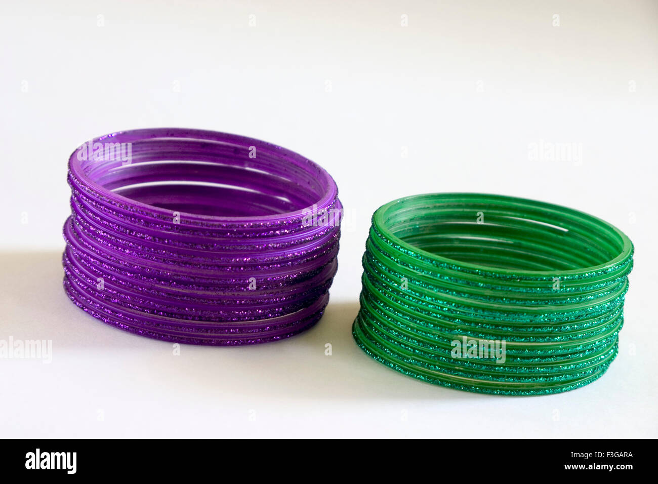 One dozen twelve round purple and green glass bangles on white background Stock Photo