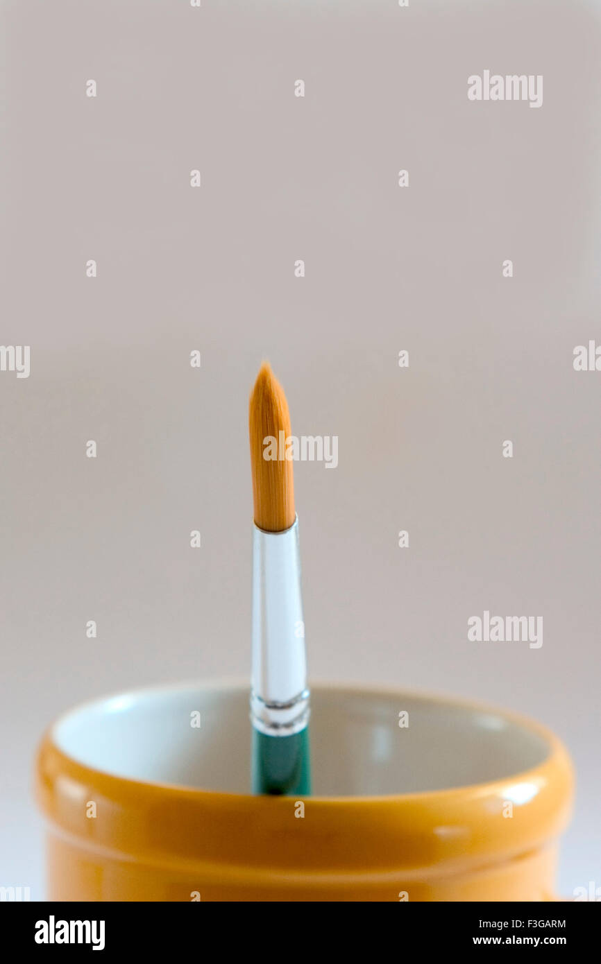 One artist paint brush in coffee mug on white background Stock Photo